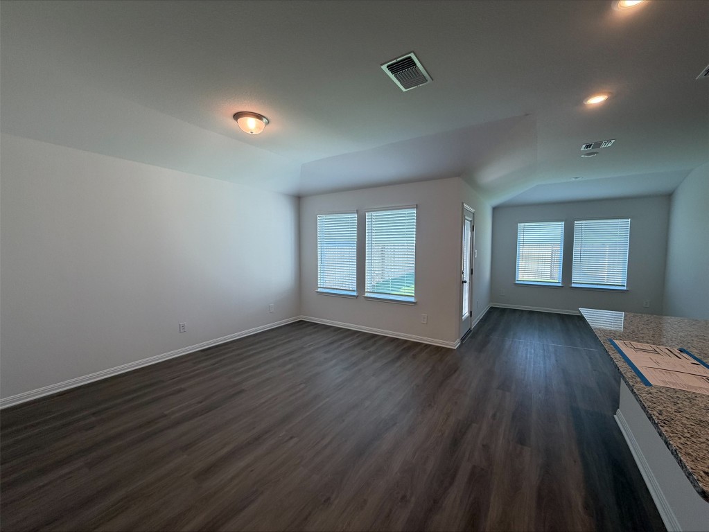 113 Honey Bee Road Jarrell, TX 76537 - Photo 7 of 10 Unfurnished living room featuring dark wood-style floors, healthy amount of natural light, and lofted ceiling
