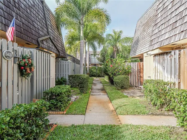 a backyard of a house with plants and trees with wooden fence