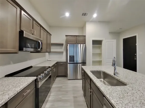 a kitchen with stainless steel appliances granite countertop a sink a stove and a refrigerator