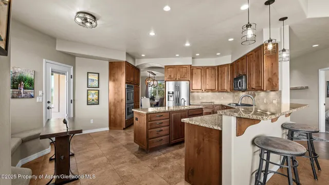 a large kitchen with kitchen island a stove a refrigerator a sink a dining table and chairs with wooden floor