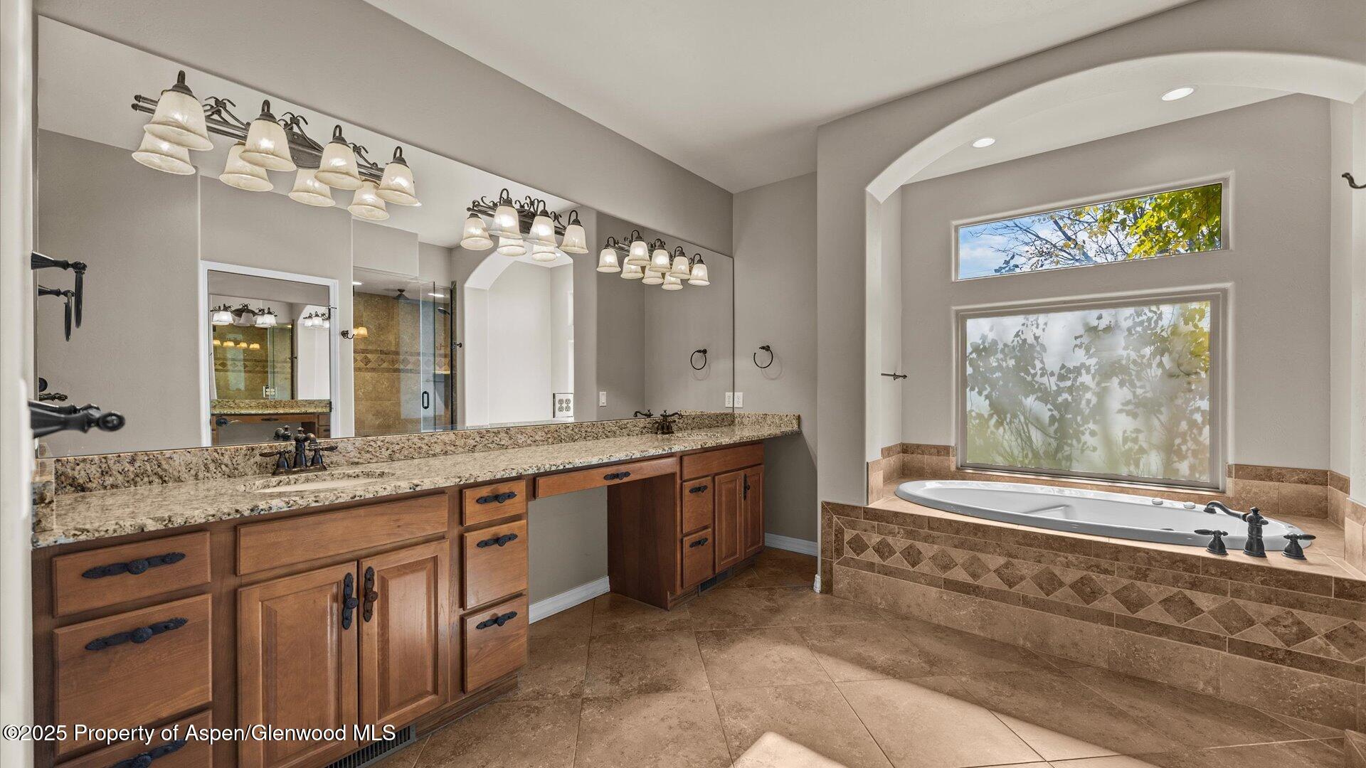 1984 J Road Fruita, CO 81521 - Photo 19 of 40 a bathroom with a granite countertop tub a double vanity sink and a large mirror