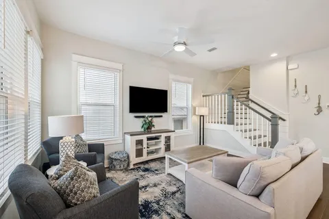 a living room with furniture flat screen tv and large window