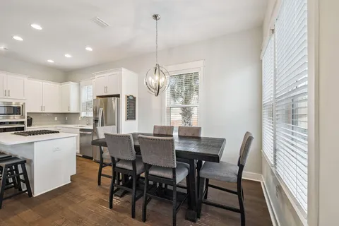 a kitchen with stainless steel appliances granite countertop a stove a sink dishwasher a dining table and chairs with wooden floor