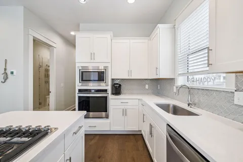a kitchen with white cabinets and appliances