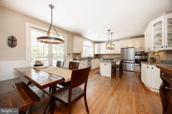 a kitchen with stainless steel appliances white cabinets a sink a stove a refrigerator and island with wooden floor
