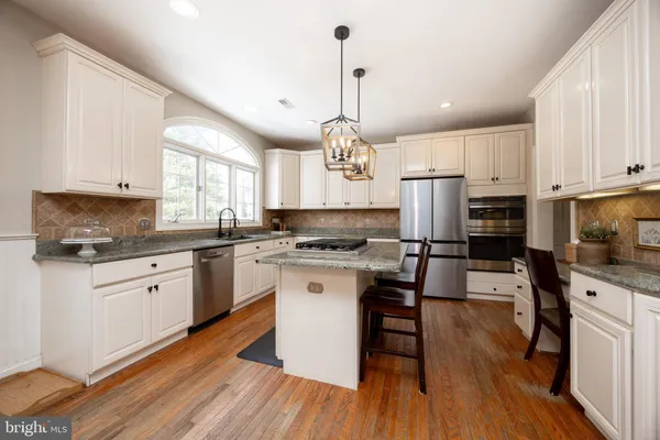 a kitchen with stainless steel appliances granite countertop wooden floor dining table and chairs