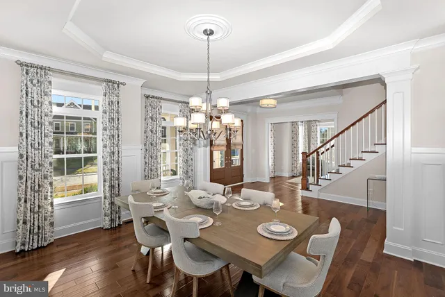 a kitchen with stainless steel appliances granite countertop a stove top oven a sink dishwasher a dining table and chairs with wooden floor