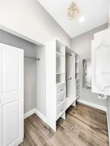 an empty room with wooden floor cabinet and windows