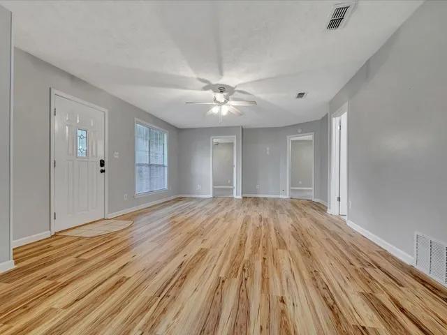 a view of empty room with wooden floor and fan