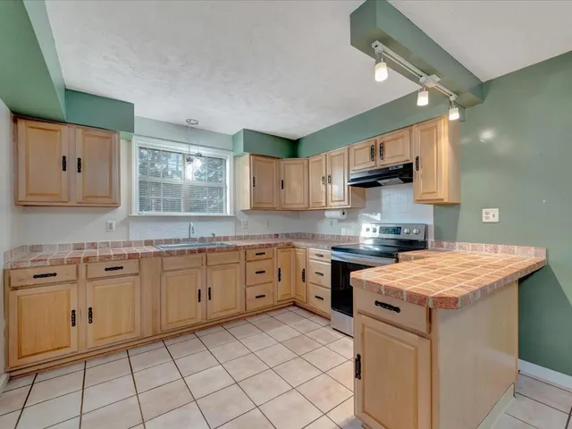 a kitchen with stainless steel appliances granite countertop a sink and dishwasher a refrigerator with white cabinets