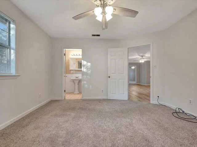 an empty room with chandelier fan and windows