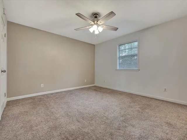 an empty room with chandelier fan and windows