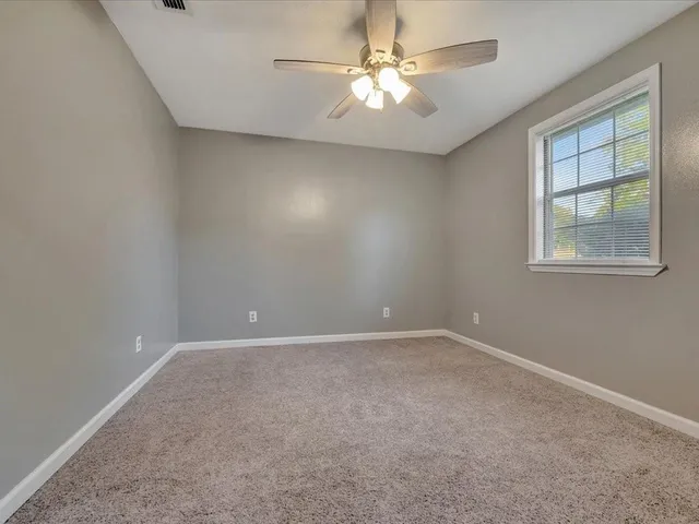 an empty room with windows and fan