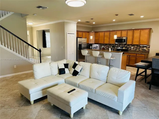 a living room with furniture kitchen view and a large window