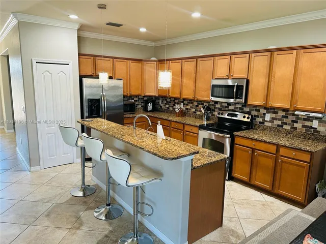 a kitchen with stainless steel appliances granite countertop a refrigerator a stove top oven a sink a dining table and chairs