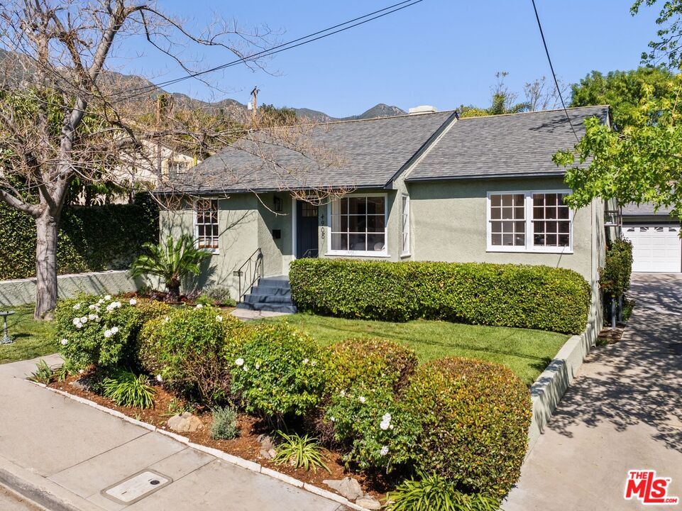 a view of a house with a small yard and potted plants