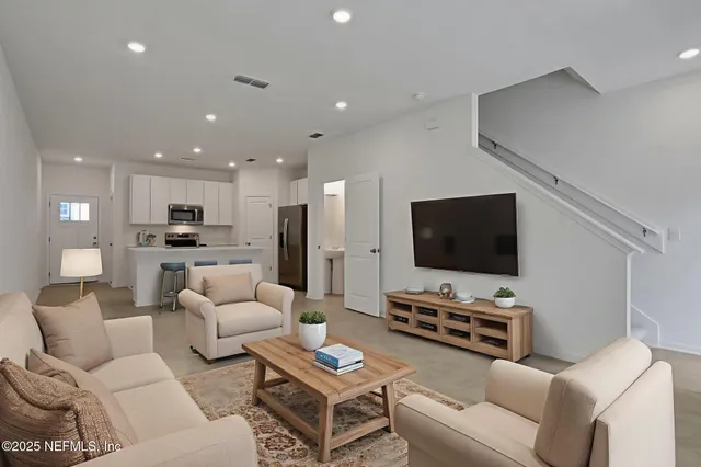 a living room with furniture and a flat screen tv with kitchen view
