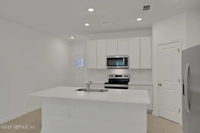 a kitchen with stainless steel appliances a stove a sink and a refrigerator