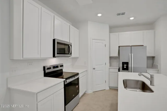 a kitchen with stainless steel appliances a refrigerator sink and microwave