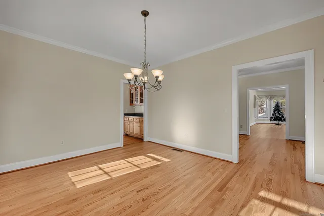 a view of a room with wooden floor chandelier and a kitchen