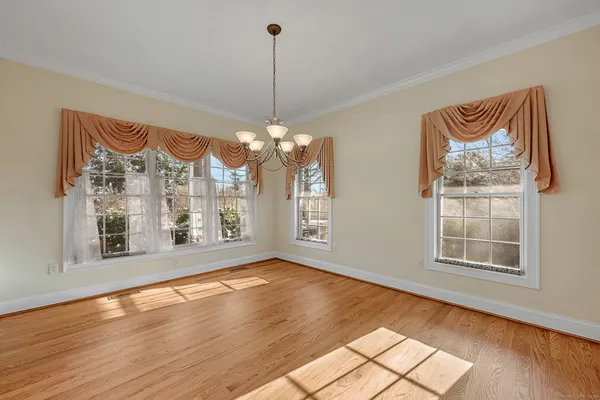 a view of a room with wooden floor chandelier and a kitchen