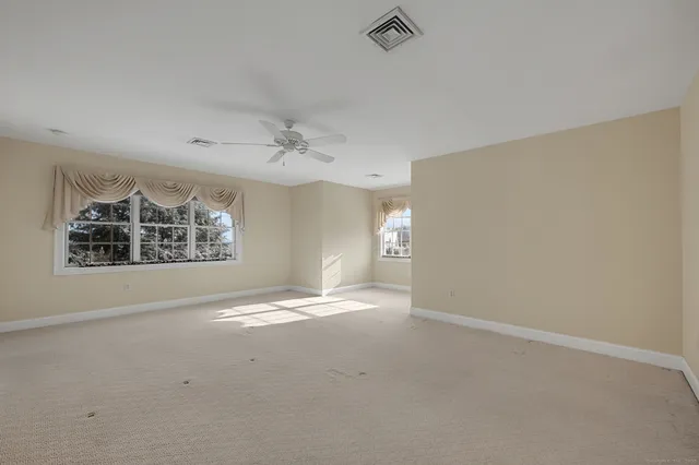 an empty room with windows and fan