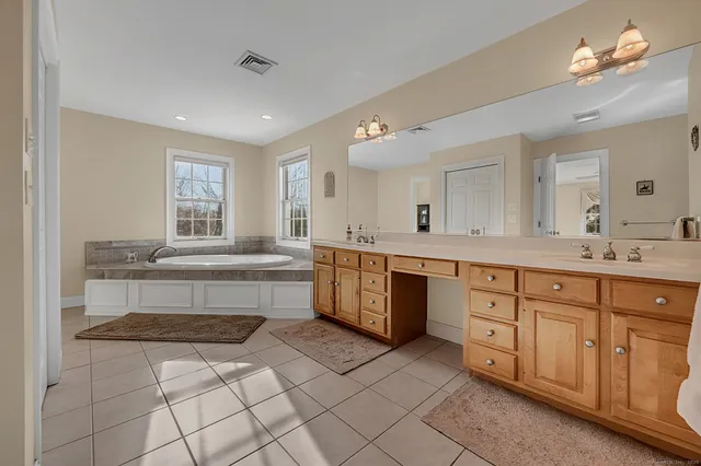 a spacious bathroom with a granite countertop double vanity sink a mirror and a bathtub