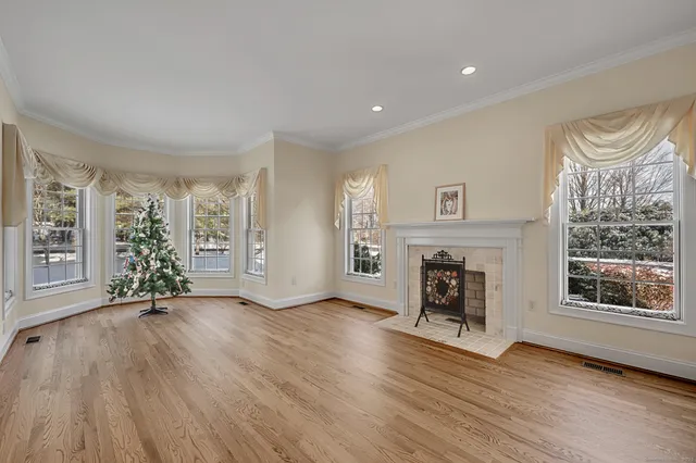 an empty room with windows a fireplace and wooden floor