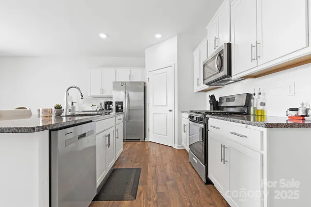 a kitchen with granite countertop a refrigerator stove top oven and sink