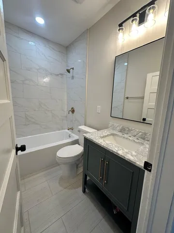a bathroom with a granite countertop sink a toilet and shower
