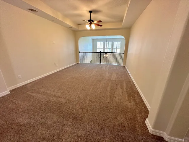 an empty room with windows and chandelier fan