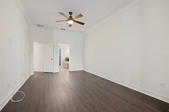 an empty room with wooden floor ceiling fan and windows