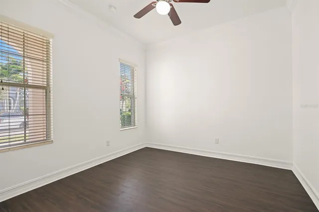 an empty room with wooden floor fan and windows