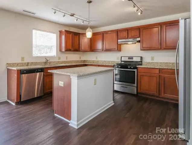 a kitchen with stainless steel appliances granite countertop a stove a sink and a microwave
