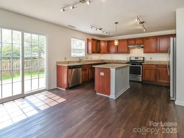 a large kitchen with stainless steel appliances granite countertop a stove and a wooden floors