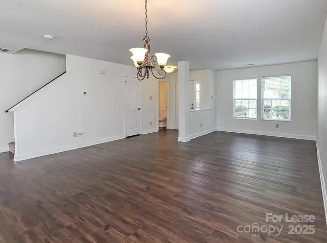 a view of a big room with wooden floor and windows