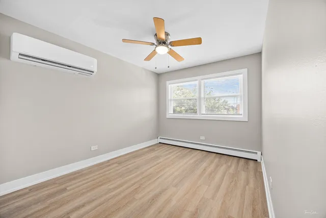 an empty room with wooden floor ceiling fan and windows
