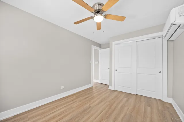 an empty room with wooden floor fan and windows