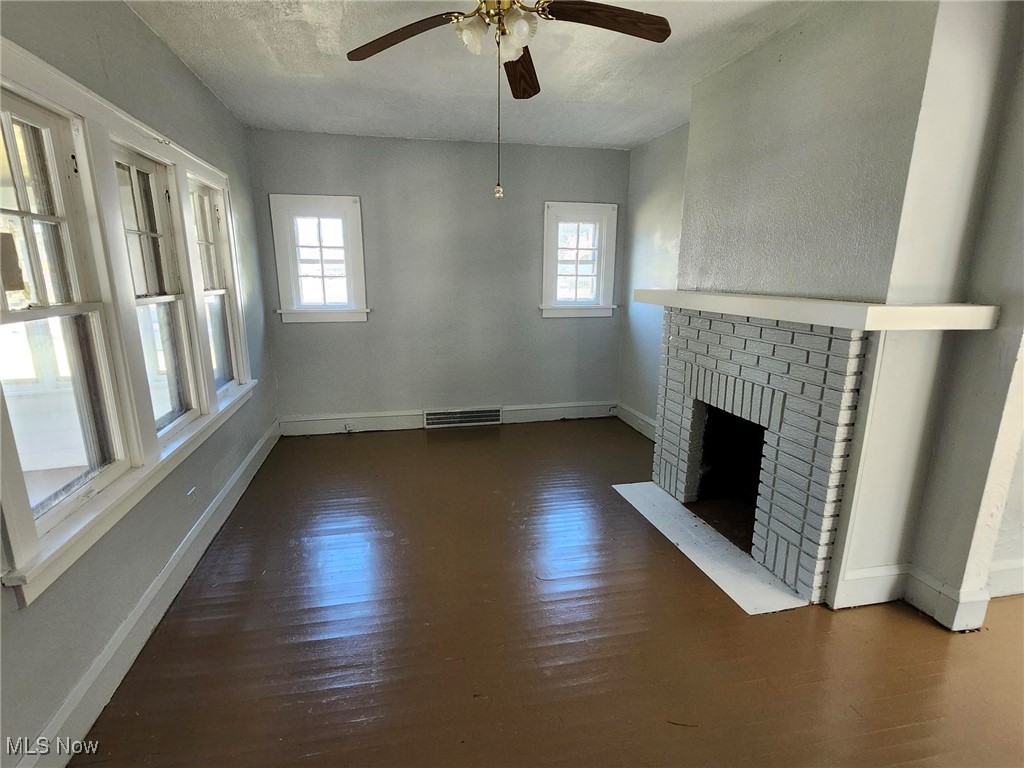 1639 Avalon Road Cleveland, OH 44112 - Photo 6 of 29 Unfurnished living room with wood finished floors, a ceiling fan, and a fireplace
