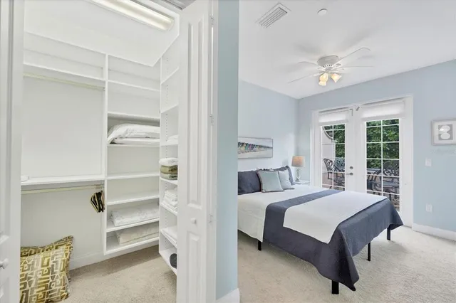 a view of yellow house with potted plants and a large tree