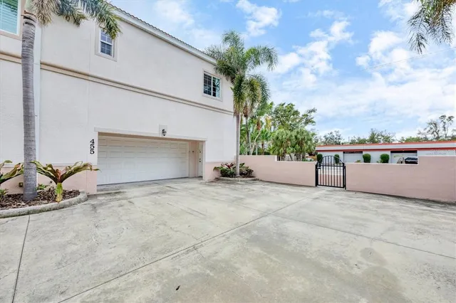 a front view of a house with a yard and palm trees