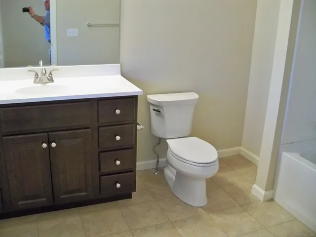 a bathroom with a toilet a sink and mirror