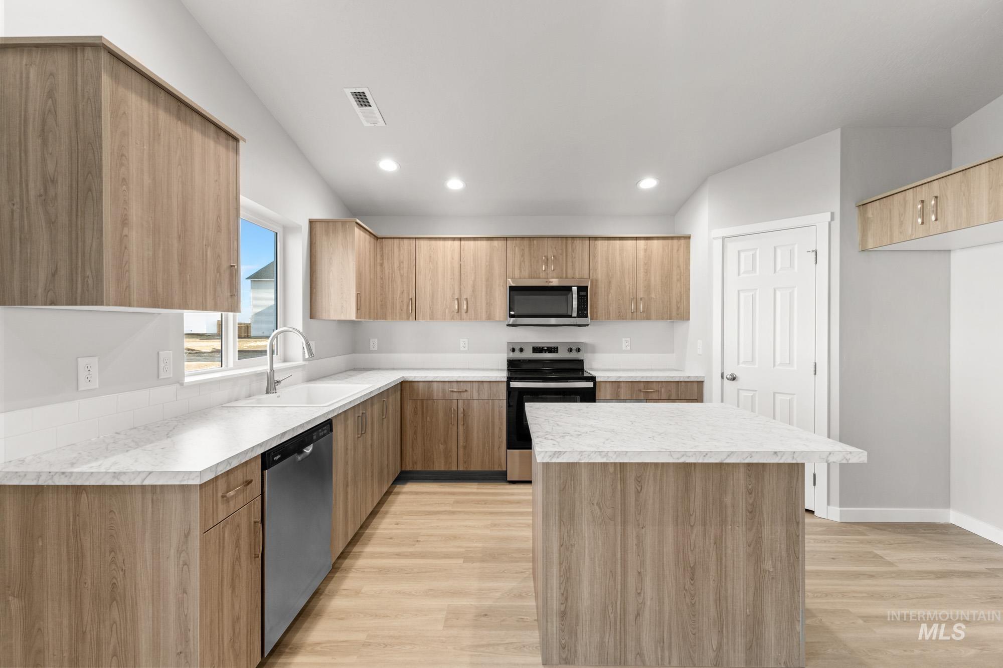 436 Merlin Court Middleton, ID 83644 - Photo 4 of 20 Kitchen featuring a central island with a light-colored countertop, wood-finish cabinetry, stainless steel appliances, and wood-finish flooring
