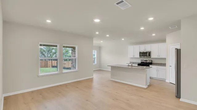 a living room with stainless steel appliances kitchen island granite countertop a stove and a refrigerator