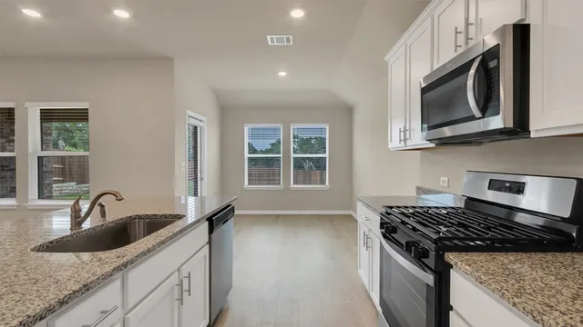 a kitchen with granite countertop a sink and a stove top oven
