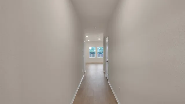 a view of a hallway with wooden floor and a bathroom