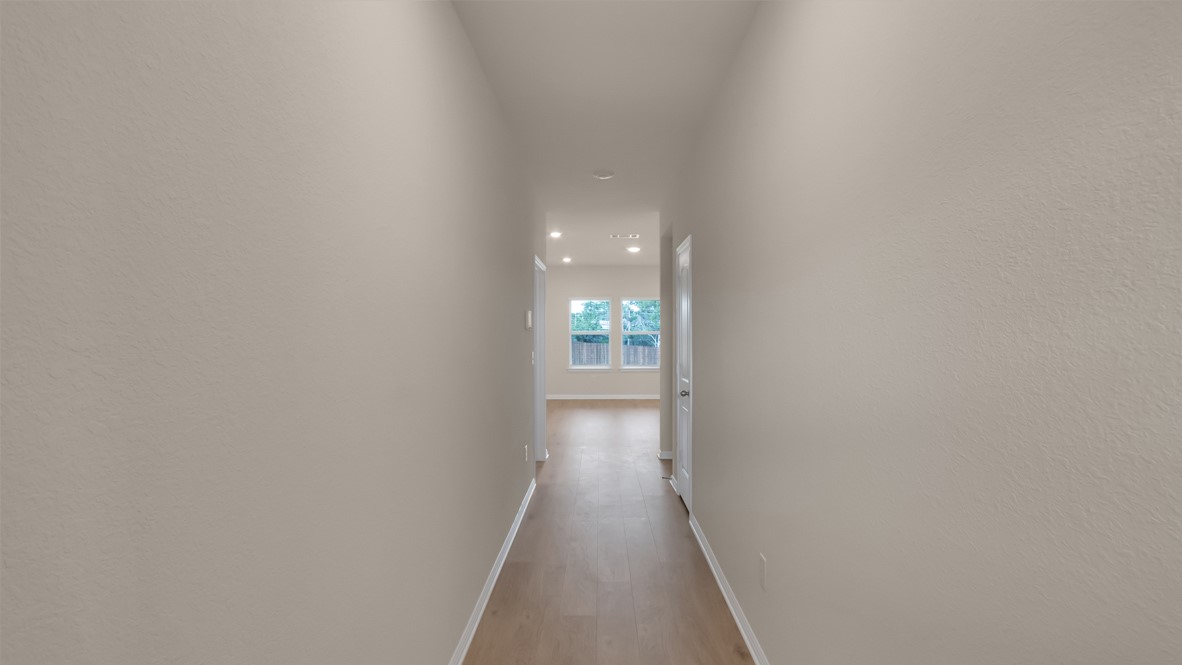 1817 Side Buster Trail Leander, TX 78641 - Photo 10 of 25 a view of a hallway with wooden floor and a bathroom