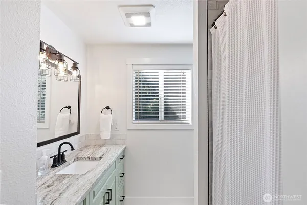 a bathroom with a granite countertop sink vanity mirror and shower
