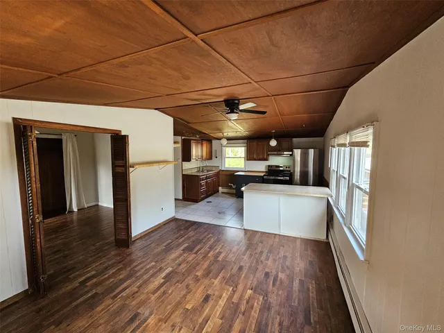 a kitchen with stainless steel appliances granite countertop a refrigerator a sink dishwasher a stove and white countertops with wooden floor