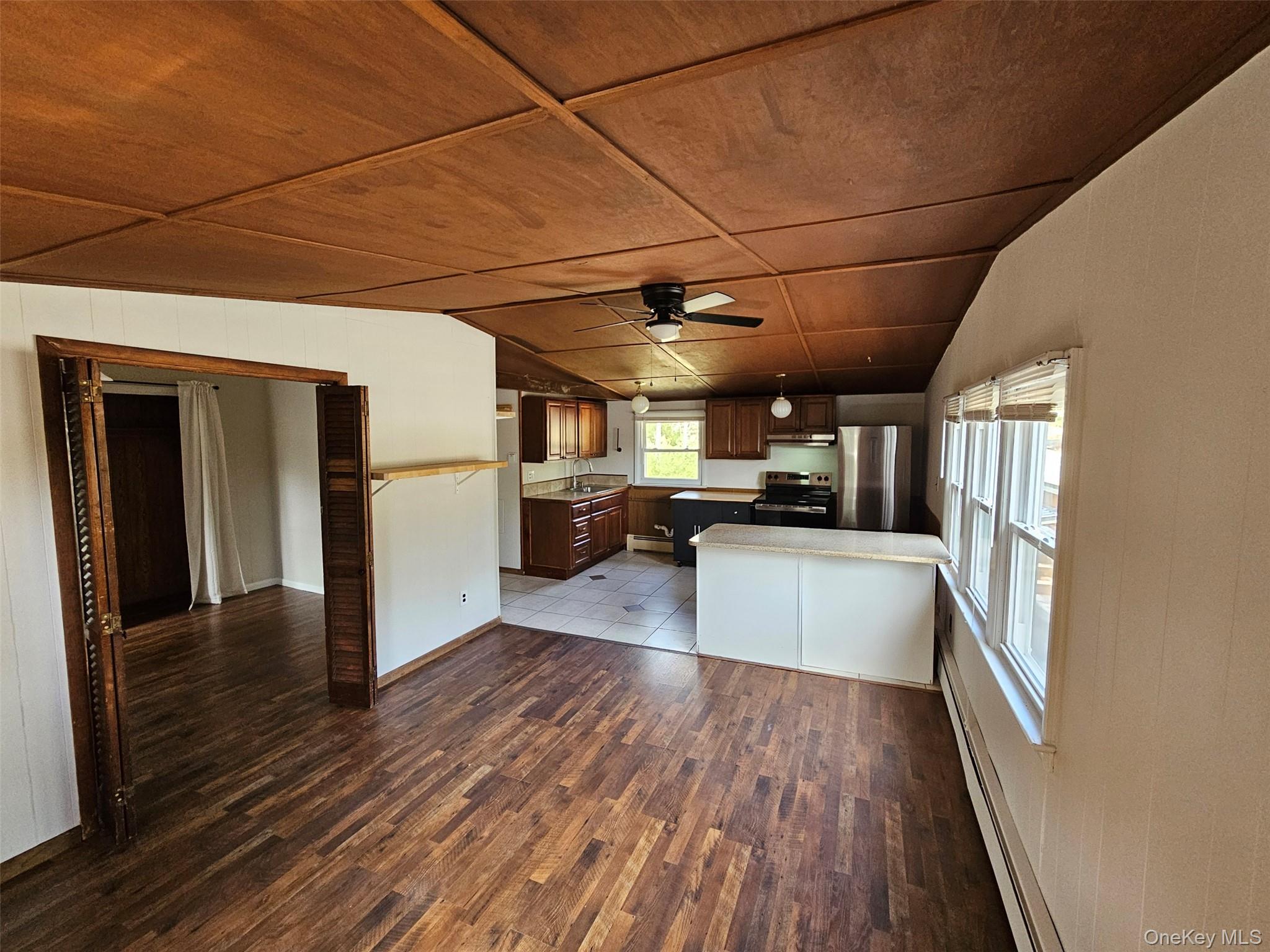 a kitchen with stainless steel appliances granite countertop a refrigerator a sink dishwasher a stove and white countertops with wooden floor